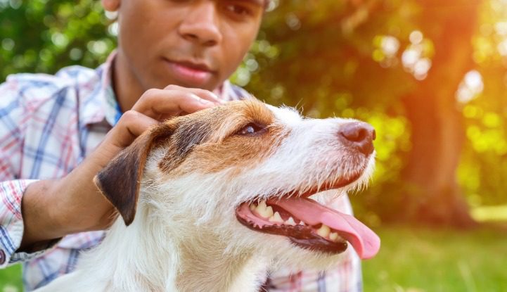 an African American male petting his dog on the head