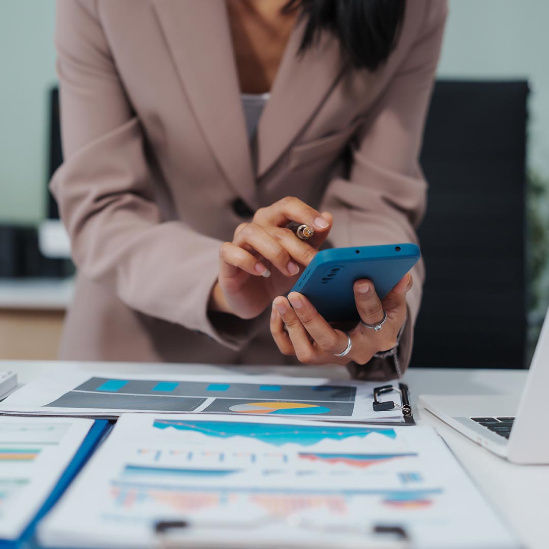 woman using calculator while looking at various spreadsheets