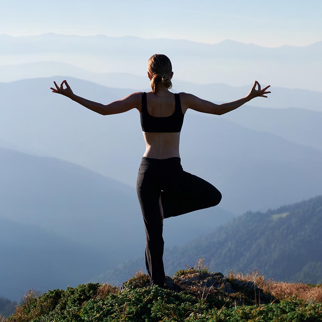 woman performing yoga pose on top of mountain